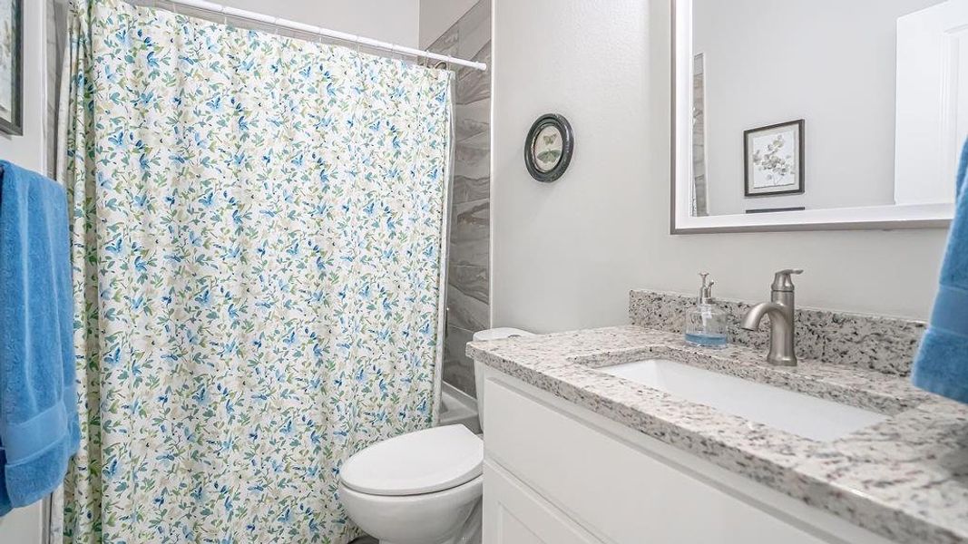 Full bathroom with vanity, toilet, and shower / bathtub combination with curtain