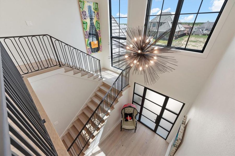 Stairway featuring a high ceiling, wood-type flooring, and an inviting chandelier