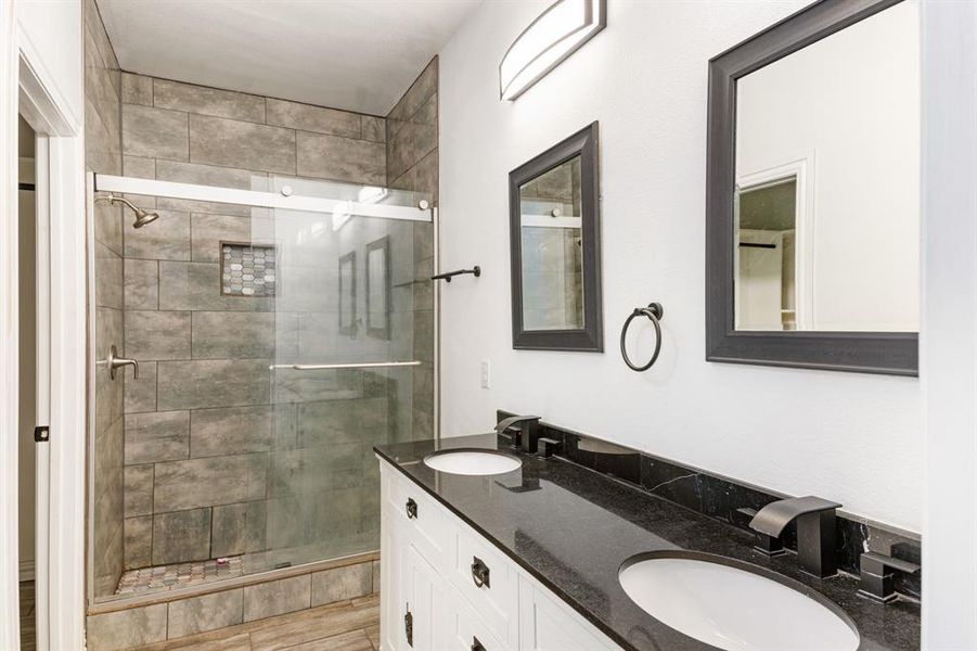 Bathroom with wood-type flooring, an enclosed shower, and vanity