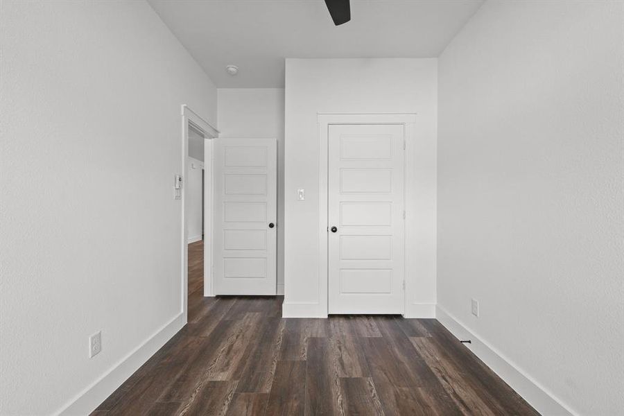 Unfurnished bedroom featuring dark wood-type flooring, ceiling fan, and a closet