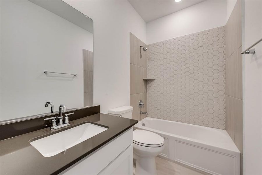 Full bathroom featuring vanity, tiled shower / bath combo, and toilet