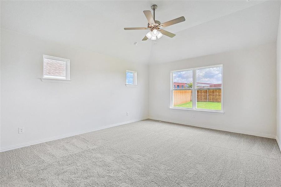 Carpeted empty room featuring vaulted ceiling and ceiling fan