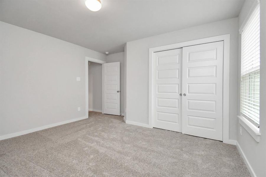 Secondary bedroom features plush carpeting, large windows that let in plenty of natural light, bright paint, and spacious closets.