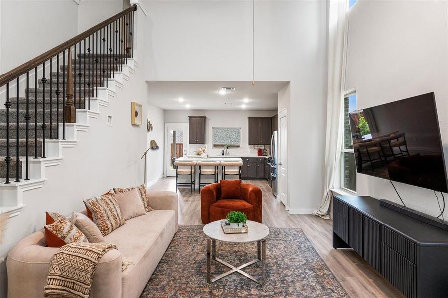 Living room featuring a towering ceiling, light hardwood / wood-style flooring, and sink