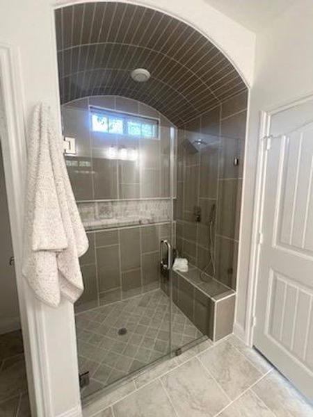 Bathroom featuring vaulted ceiling and an enclosed shower