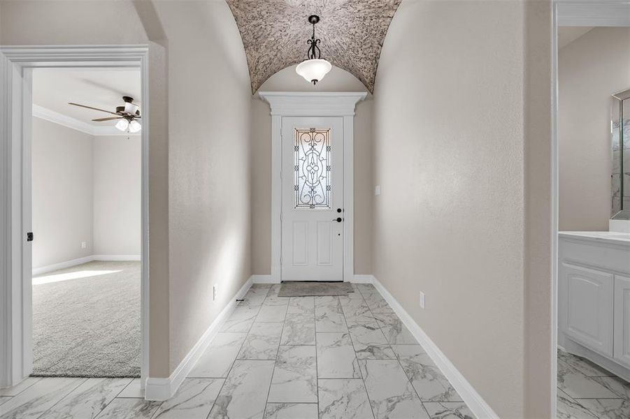 Foyer entrance with light colored carpet, ceiling fan, lofted ceiling, and ornamental molding