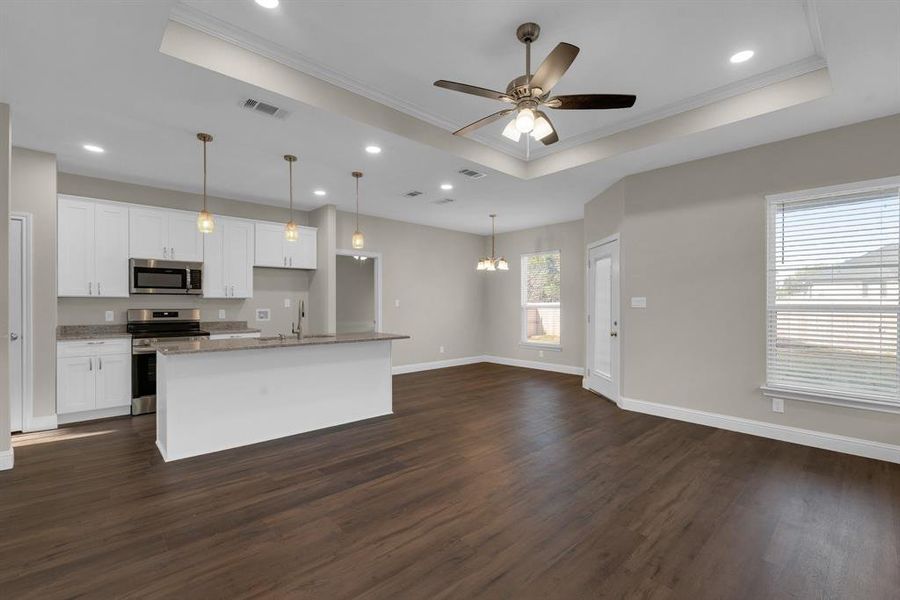 Kitchen featuring white cabinets, a kitchen island with sink, appliances with stainless steel finishes, and dark hardwood / wood-style flooring