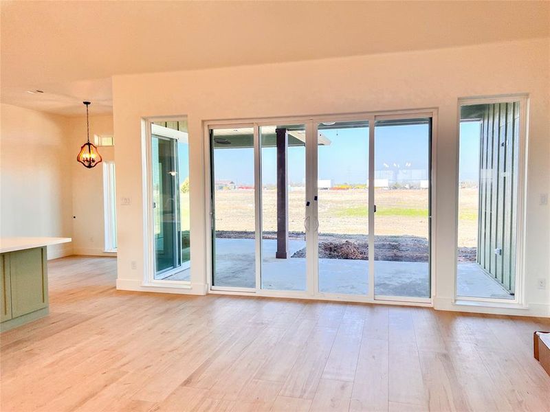 Living room with light hardwood / wood-style floors and big sliding windows to back patio