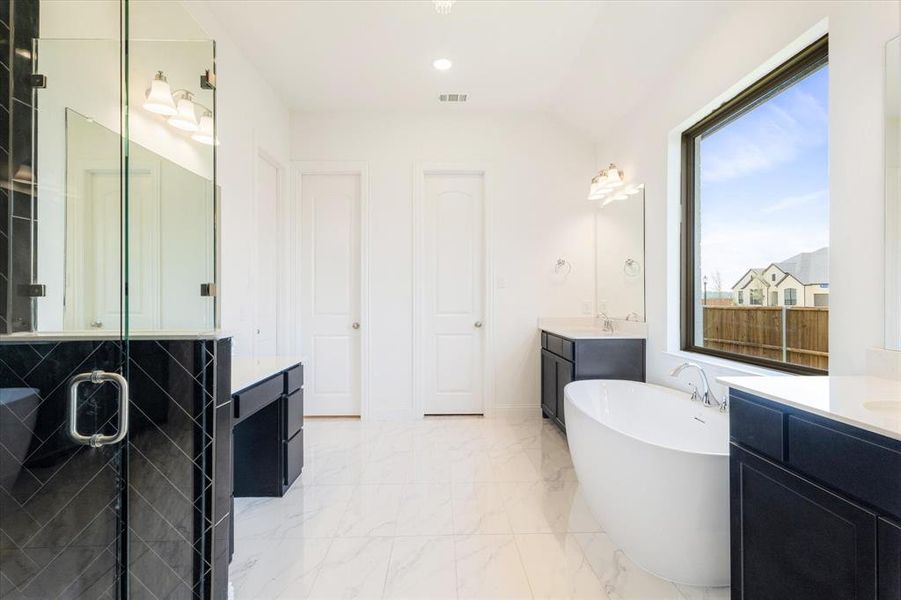 Bathroom with tile floors, plenty of natural light, dual bowl vanity, and a stand alone tub