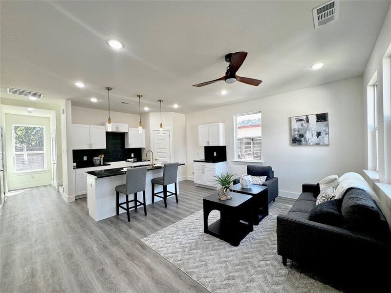 Living room featuring ceiling fan, light hardwood / wood-style flooring, sink, and a healthy amount of sunlight