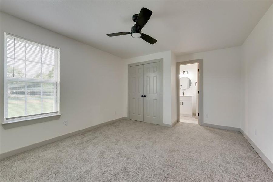 Unfurnished bedroom featuring a closet, ceiling fan, connected bathroom, and light colored carpet