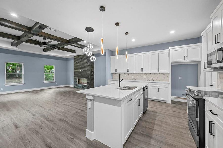 Kitchen featuring coffered ceiling, decorative light fixtures, sink, ceiling fan, and white cabinets