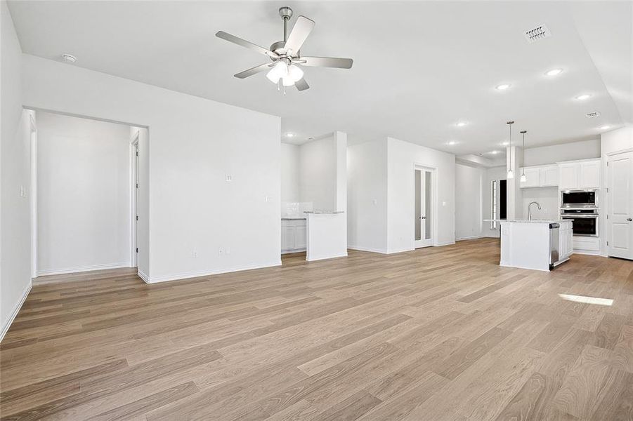 Unfurnished living room featuring light hardwood / wood-style floors, ceiling fan, and sink