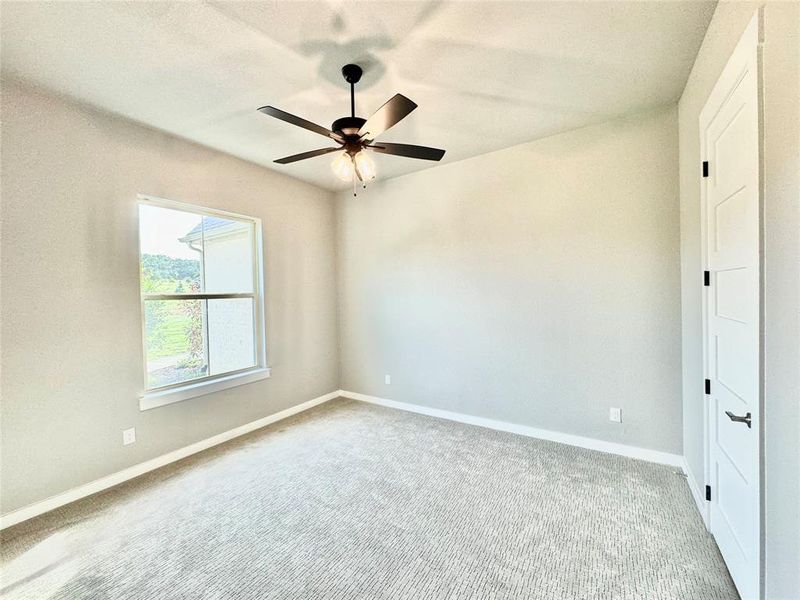 Carpeted secondary room with ceiling fan