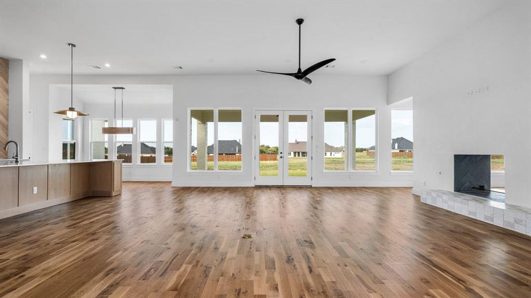 Unfurnished living room featuring dark hardwood / wood-style flooring, ceiling fan, sink, and plenty of natural light