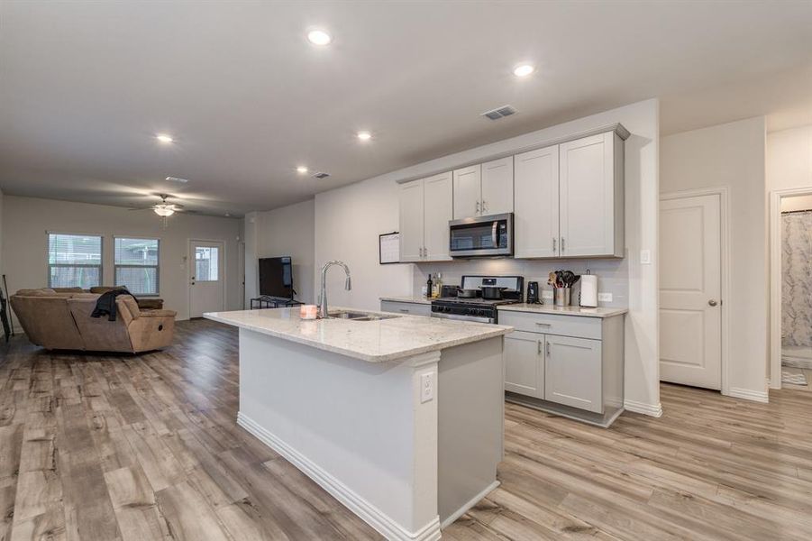 Kitchen featuring ceiling fan, an island with sink, sink, light hardwood / wood-style flooring, and stainless steel appliances