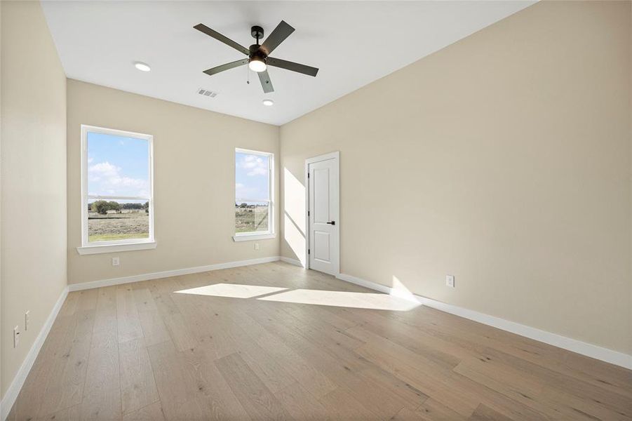 Empty room with light hardwood / wood-style floors and ceiling fan