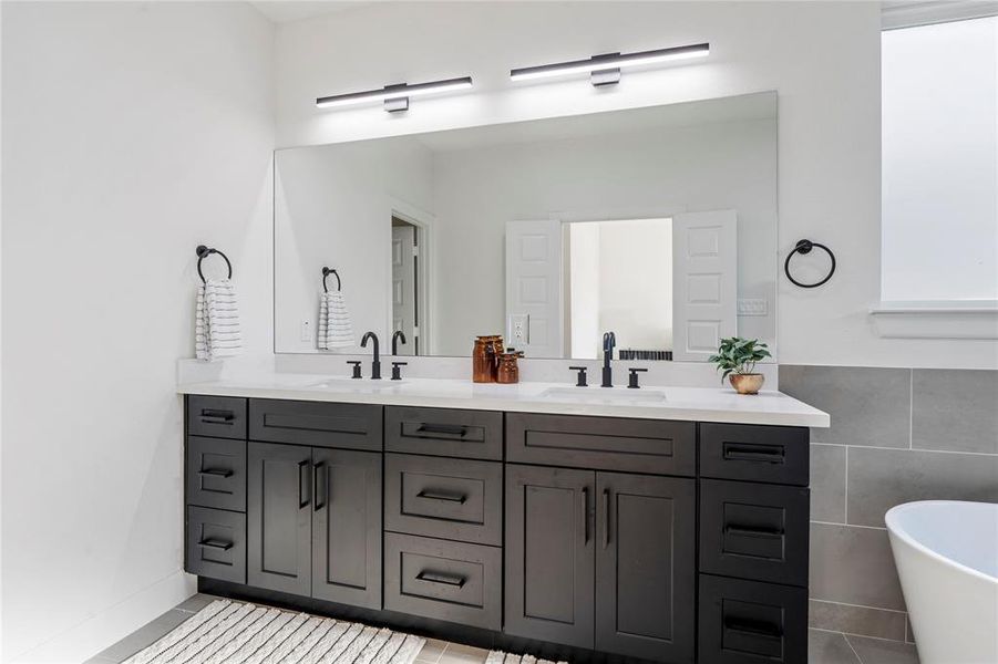 Elegance and practicality in this lavish bathroom, boasting expansive quartz countertops with his-and-hers sinks, ample storage with drawers, and generous cabinet space. Designed for ultimate comfort and organized living.