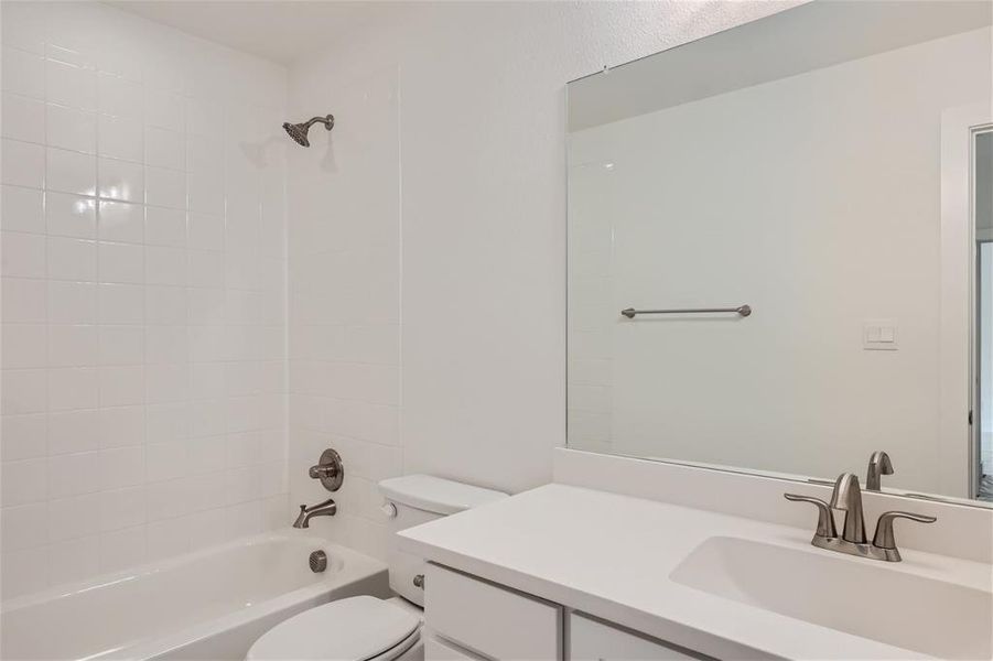 Full bathroom featuring tiled shower / bath, oversized vanity, and toilet