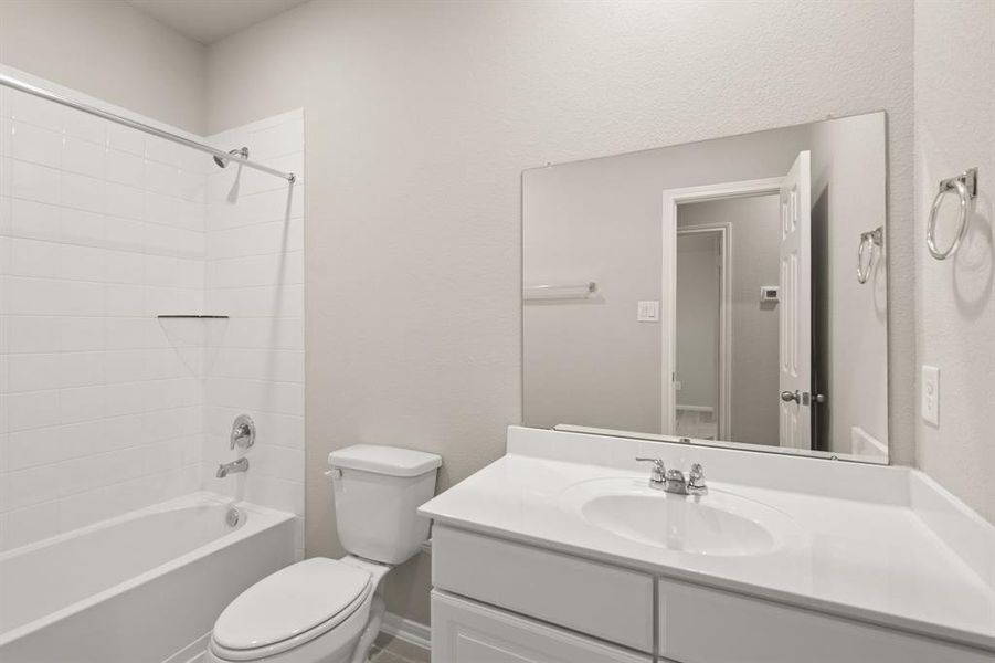 The secondary bath features tile flooring, white cabinetry and light countertops and a shower/tub combo. Perfect for accommodating any visiting family and friends.