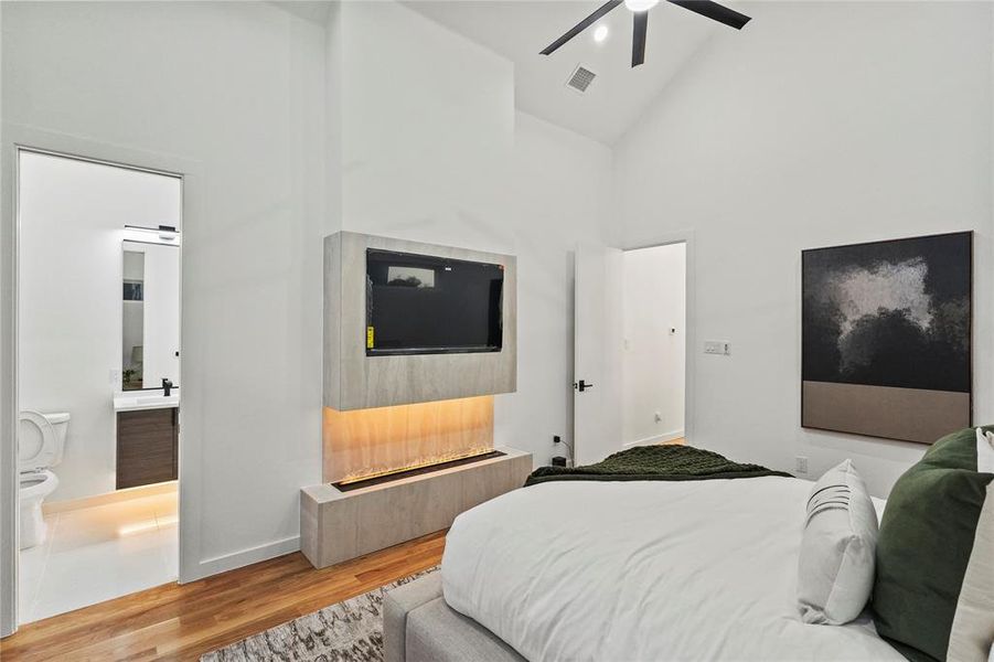 Bedroom featuring wood-type flooring, connected bathroom, high vaulted ceiling, and ceiling fan