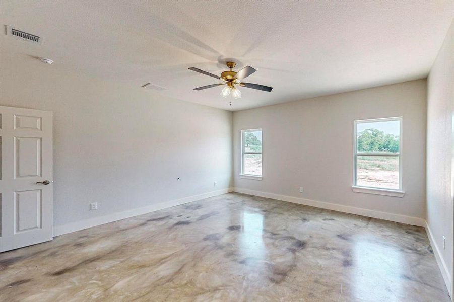 Spare room with a textured ceiling, ceiling fan, and a wealth of natural light