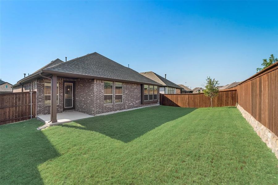 Back of house with a lawn and a patio