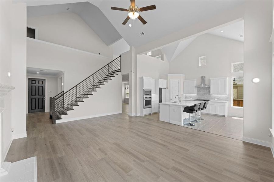 Unfurnished living room with ceiling fan, high vaulted ceiling, light hardwood / wood-style floors, and sink