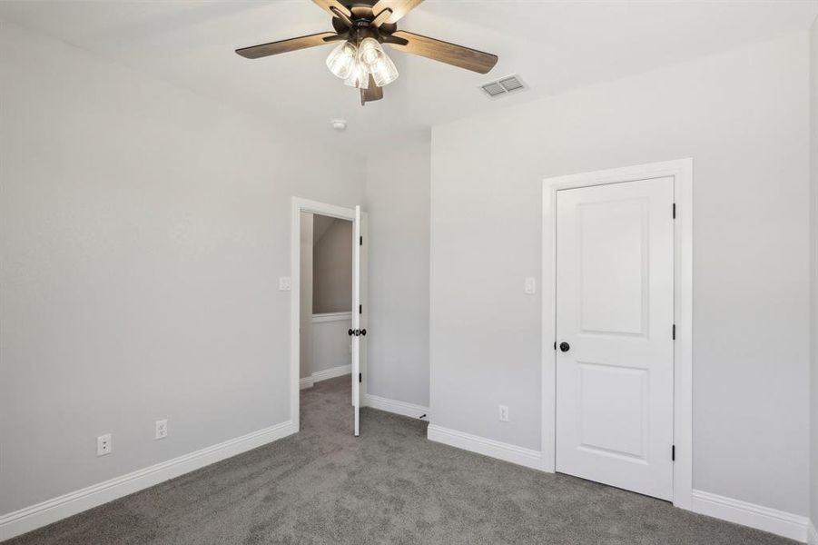 Unfurnished bedroom with ceiling fan and carpet flooring