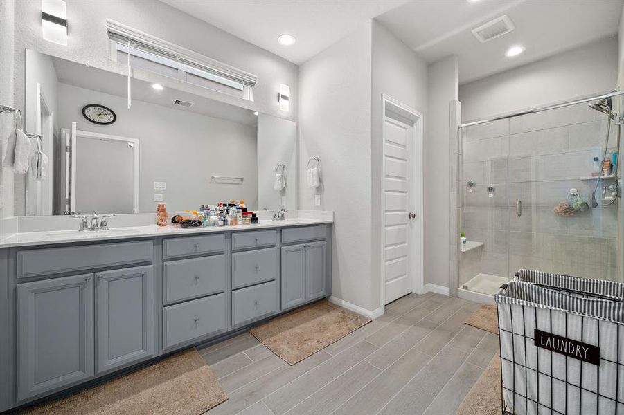 This primary bathroom is definitely move-in ready! Featuring a framed oversized walk-in shower with tile surround, grey cabinets with Quartz countertops, spacious walk-in closet with shelving, high ceilings, custom paint, sleek and modern finishes.