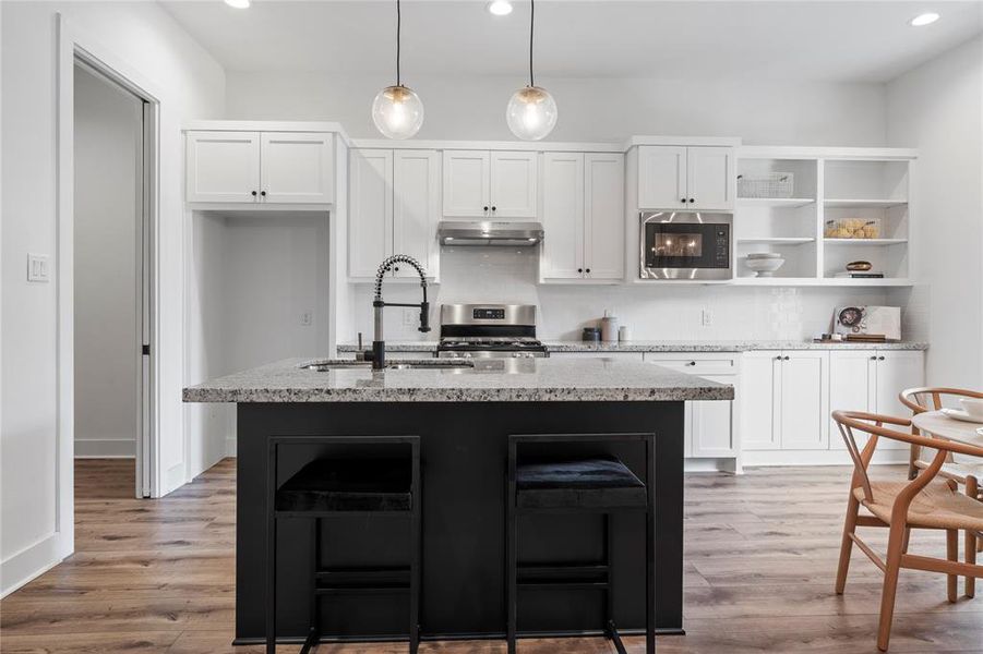 This view showcases the heart of the home, the kitchen, with its stylish black island, plentiful cabinet storage, and natural light flooding in from the adjacent back door, creating a warm and welcoming environment