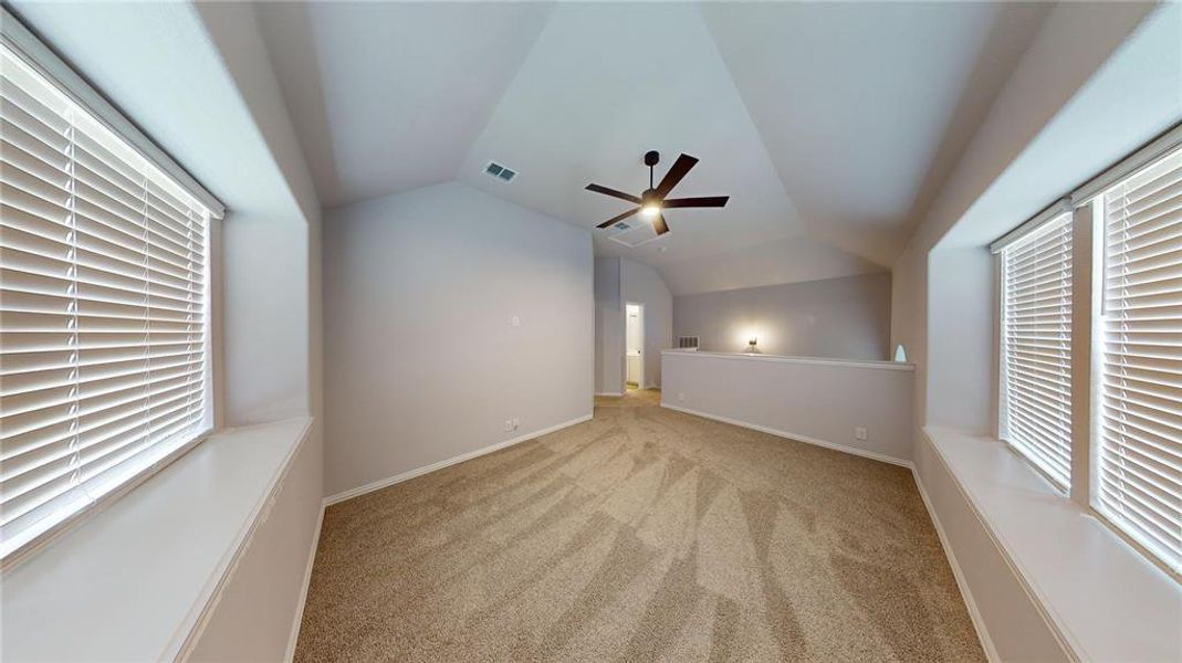 Additional living space featuring light carpet, lofted ceiling, and ceiling fan