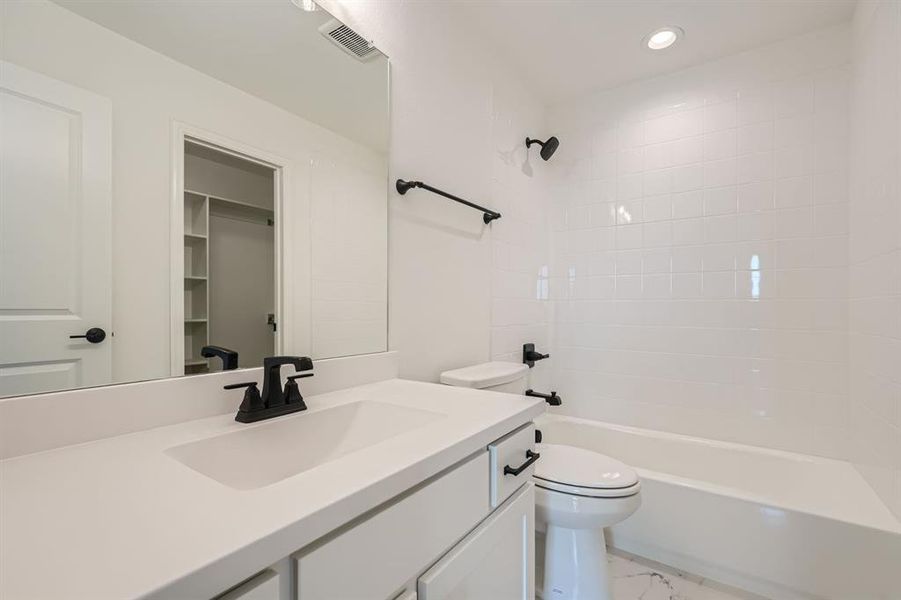 Full bathroom with tile patterned flooring, toilet, vanity, and tiled shower / bath