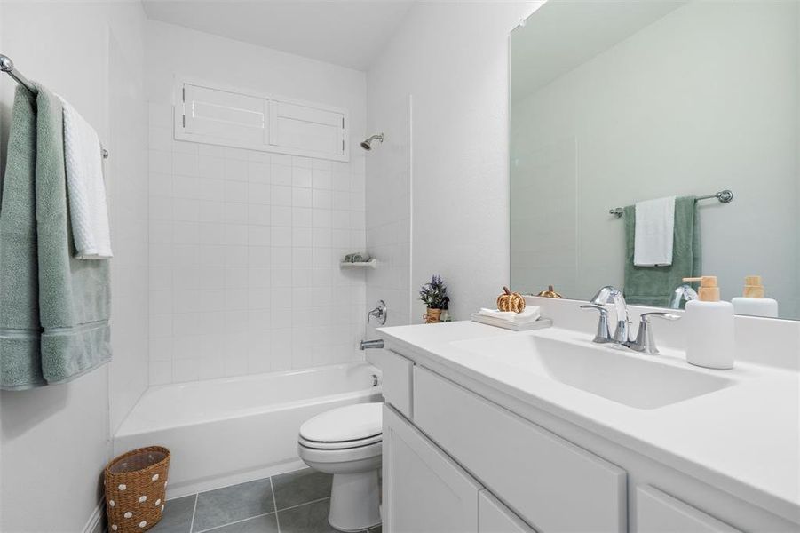 Full bathroom with vanity, tiled shower / bath combo, toilet, and tile patterned flooring