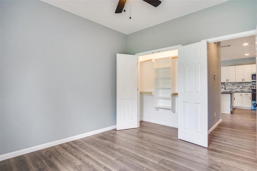 Unfurnished bedroom featuring a spacious closet, wood-type flooring, and ceiling fan