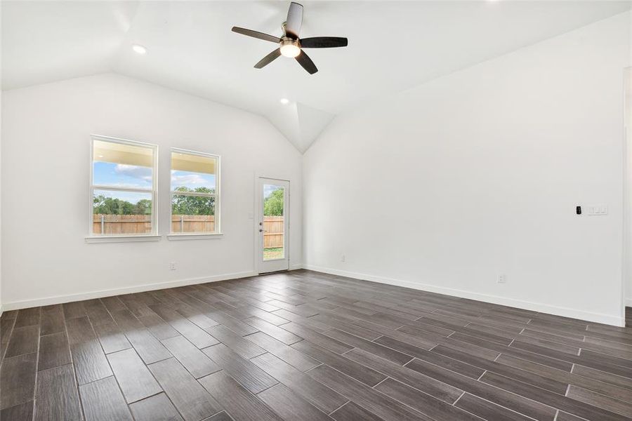 Empty room featuring ceiling fan, dark hardwood / wood-style floors, and vaulted ceiling