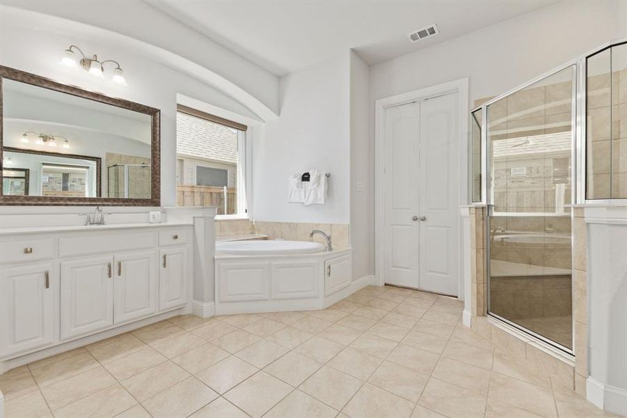 Bathroom featuring tile flooring, shower with separate bathtub, and oversized vanity
