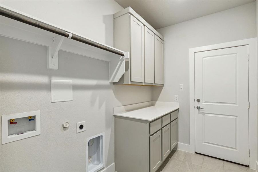 Laundry room featuring hookup for an electric dryer, hookup for a washing machine, cabinets, and light tile patterned flooring