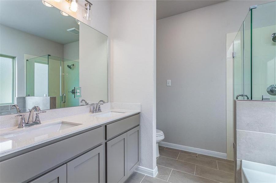 A touch of luxury in the primary suite, the bathroom features dual sinks with elegant fixtures, a spacious vanity with ample storage, and a large mirror that adds a sense of depth and space. The modern design creates a spa-like ambiance for daily relaxation. **This image is from another Saratoga Home - Mockingbird floorplan.**