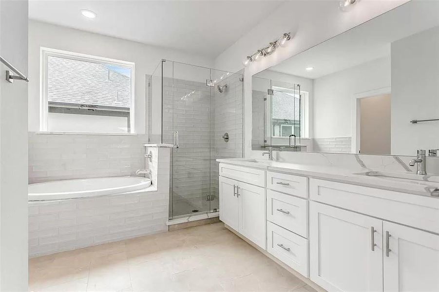 Bathroom featuring tile patterned floors, separate shower and tub, a wealth of natural light, and double sink vanity