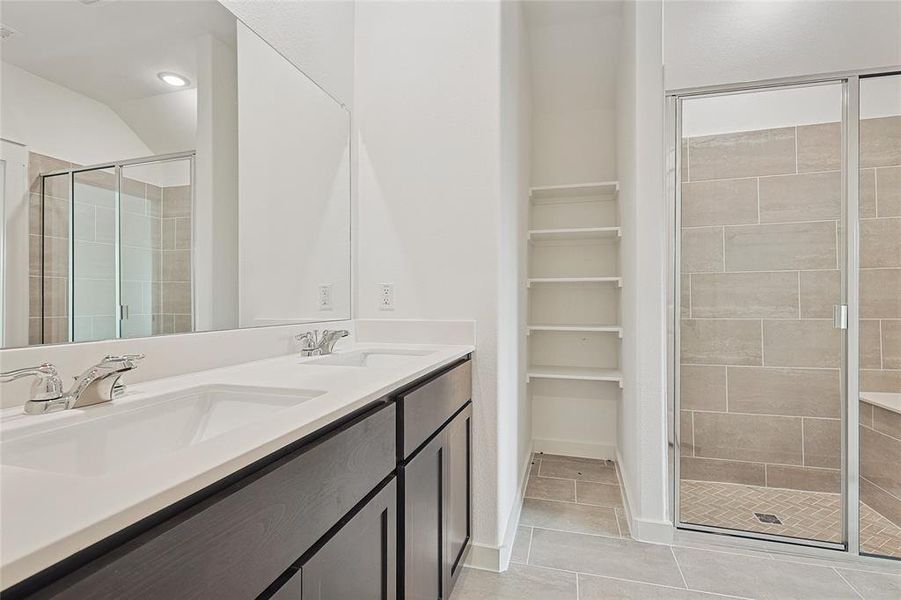 Bathroom with vanity, a shower with shower door, and tile patterned flooring