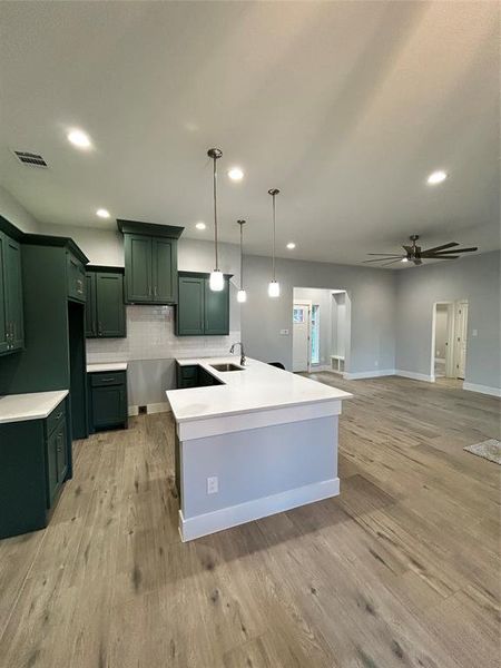 Kitchen with light hardwood / wood-style flooring, sink, and hanging light fixtures