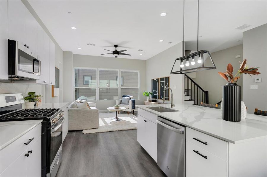 Kitchen featuring decorative light fixtures, white cabinetry, stainless steel appliances, dark hardwood / wood-style flooring, and sink