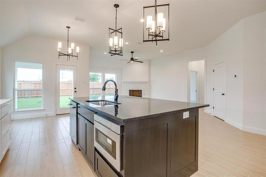 Kitchen with hanging light fixtures, dark brown cabinetry, sink, and a healthy amount of sunlight