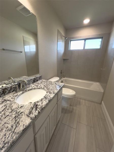 Full bathroom featuring vanity, toilet, and tiled shower / bath