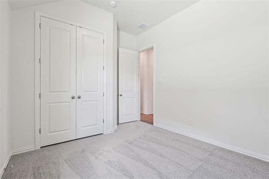 Unfurnished bedroom featuring light carpet and a closet