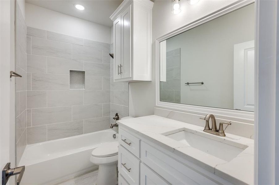 Full bathroom with vanity, tiled shower / bath combo, and toilet