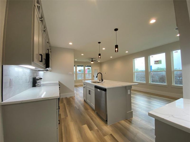 Kitchen with dishwasher, light wood-type flooring, sink, ceiling fan, and a center island with sink