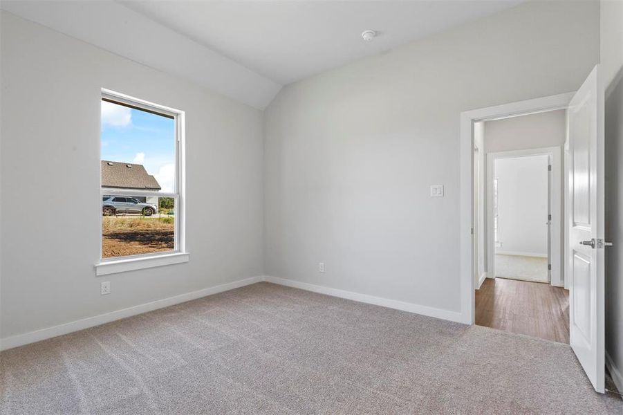 Spare room with a healthy amount of sunlight, vaulted ceiling, and wood-type flooring