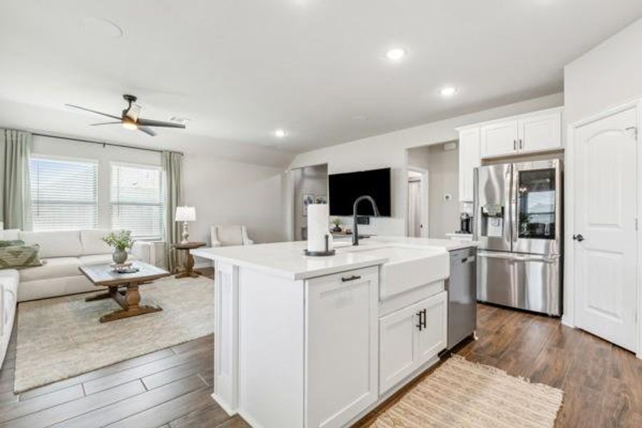 Kitchen with white cabinetry, hardwood / wood-style flooring, ceiling fan, appliances with stainless steel finishes, and a kitchen island with sink